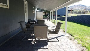 A covered patio area with outdoor furniture, a brick pathway, and a view of a mountain. - Clean, fully stocked home in Mitchell. (Mitchell)