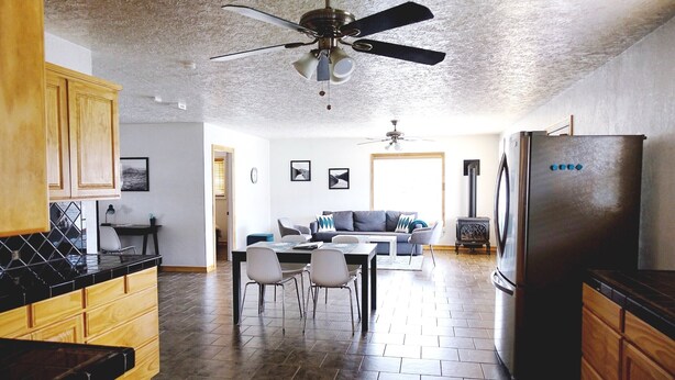 A modern kitchen with a dining area, wooden cabinets, a black refrigerator, and a ceiling fan. - Clean, fully stocked home in Mitchell. (Mitchell)