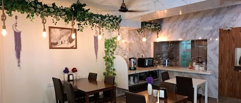 A modern dining area with a marble countertop, a ceiling fan, and hanging plants.
