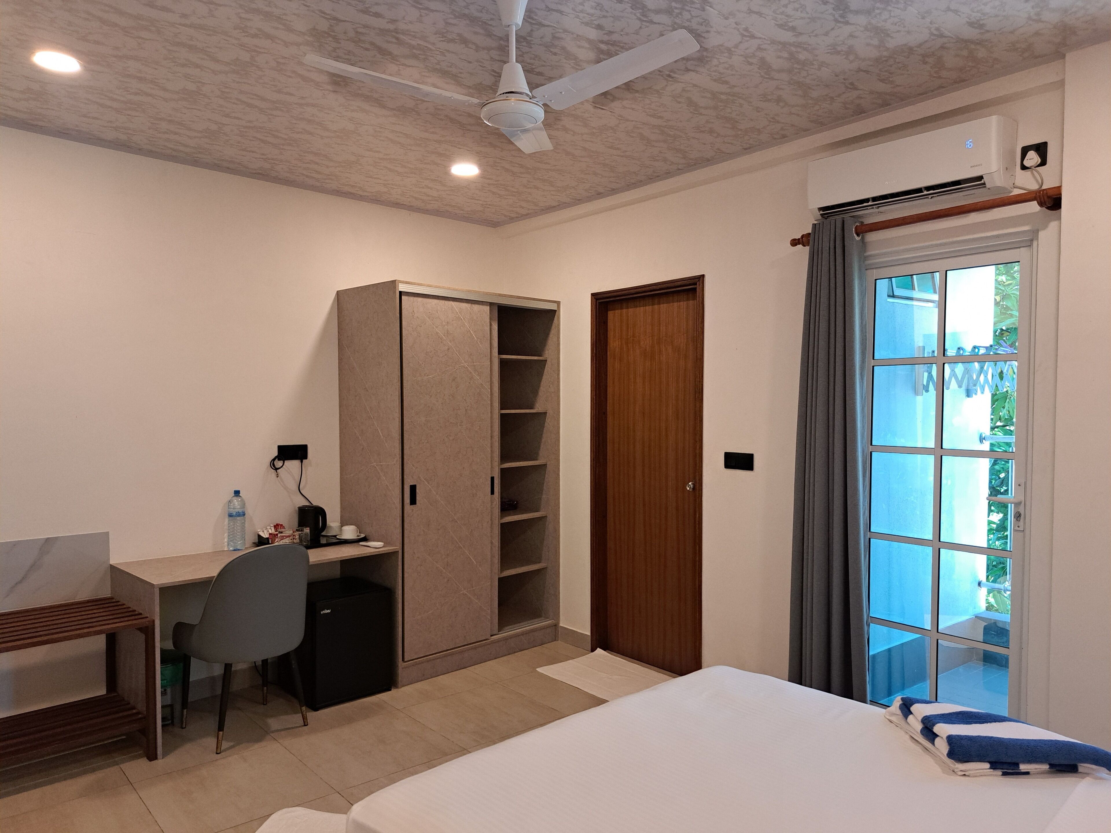 Une chambre à coucher comprenant un lit, un bureau, une armoire et un ventilateur de plafond.