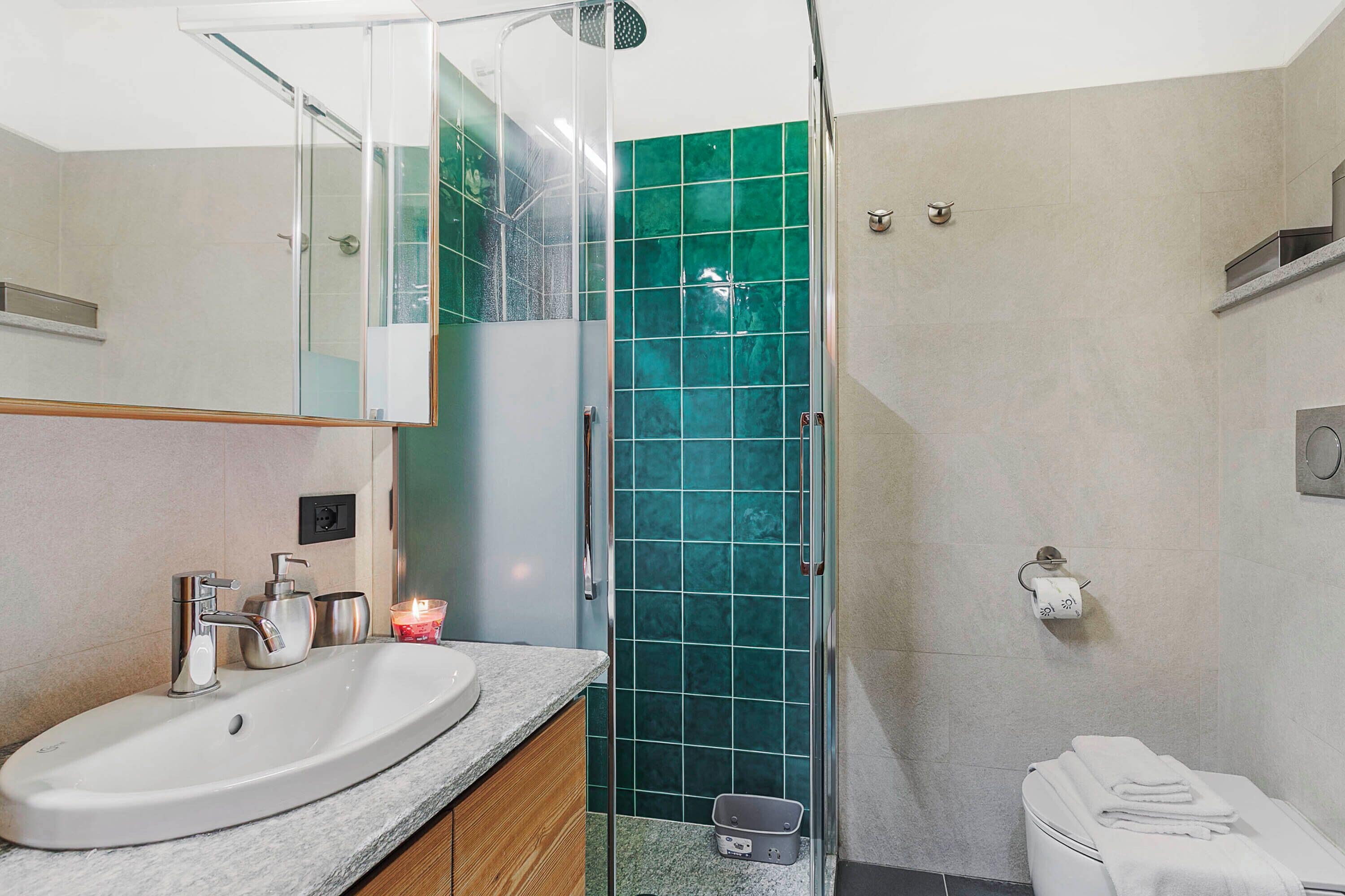 Une salle de bain avec un lavabo blanc, une douche en verre et des toilettes.