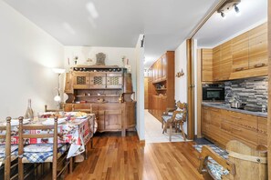 Une cuisine compacte avec des meubles en bois, une table à manger avec des chaises et un four encastré.