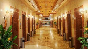 Ein Hotelgang mit mehreren Türen, einem Marmorboden und einer Decke mit eingelassener Beleuchtung und Zierelementen.