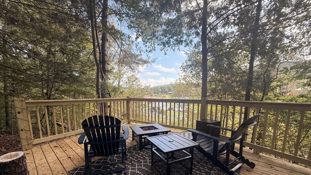 A wooden deck with a view of a forest and distant buildings.
