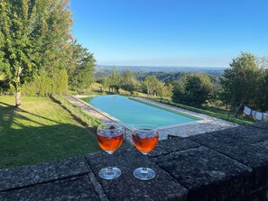 A stone bench overlooking a swimming pool with a scenic view of trees and hills. - To be awakened by the sound of birdsong (Sabadel-Latronquière)