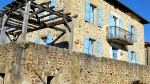 Ein Steinhaus mit einem Holzbalkon und blauen Fensterläden.