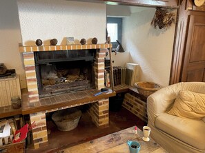 A brick fireplace with a mantel shelf, a wicker basket, and a leather couch.
