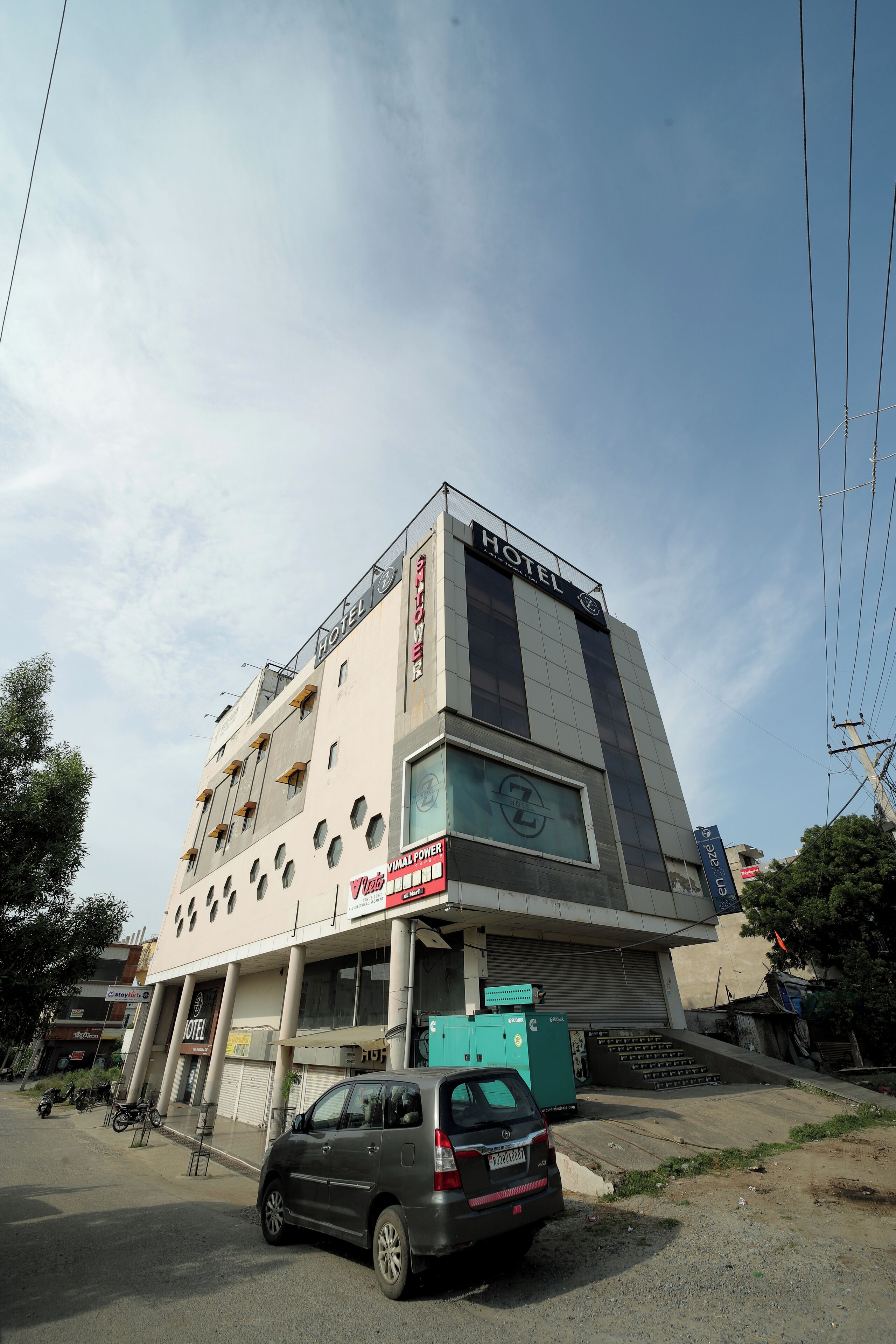 A hotel building with a sign indicating it is a unit of a hotel chain. There are multiple windows on the facade, and a car is parked in front.
