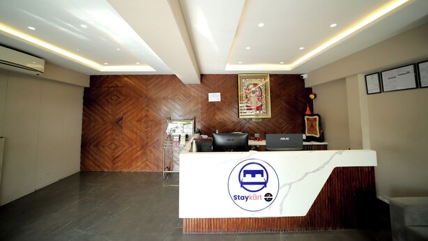 A reception area with a wooden herringbone wall, a reception desk with a logo, and a framed picture on the wall. - Staykart Z (Bhilwara)