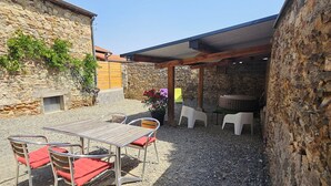 An outdoor patio with a table and chairs, a covered seating area, and a stone wall. - Winegrower's house, private courtyard, 4 people/2 beds (Prompsat)