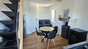 A modern kitchen with a dining area, a black staircase, and a loft bedroom with a wooden ceiling. - Winegrower's house, private courtyard, 4 people/2 beds (Prompsat)