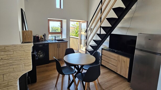 A modern kitchen with a dining area, wooden flooring, a built-in stove, and a staircase leading to an upper level. - Winegrower's house, private courtyard, 4 people/2 beds (Prompsat)