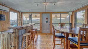 A spacious room with a wooden bar, high ceiling, large windows, and a view of the outdoors. - Spectacular views of the valley with a pool and spacious home (Concan)