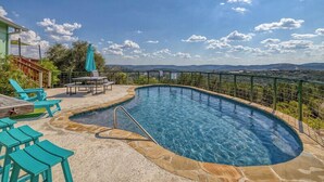 A swimming pool with a stone border, surrounded by a fence and a view of distant hills. - Spectacular views of the valley with a pool and spacious home (Concan)