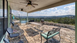 A covered outdoor area with stone flooring, a ceiling fan, a table, chairs, and a view of the landscape. - Spectacular views of the valley with a pool and spacious home (Concan)