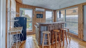 A rustic interior with a wooden bar area, bar stools, and a metal shelf unit. - Spectacular views of the valley with a pool and spacious home (Concan)