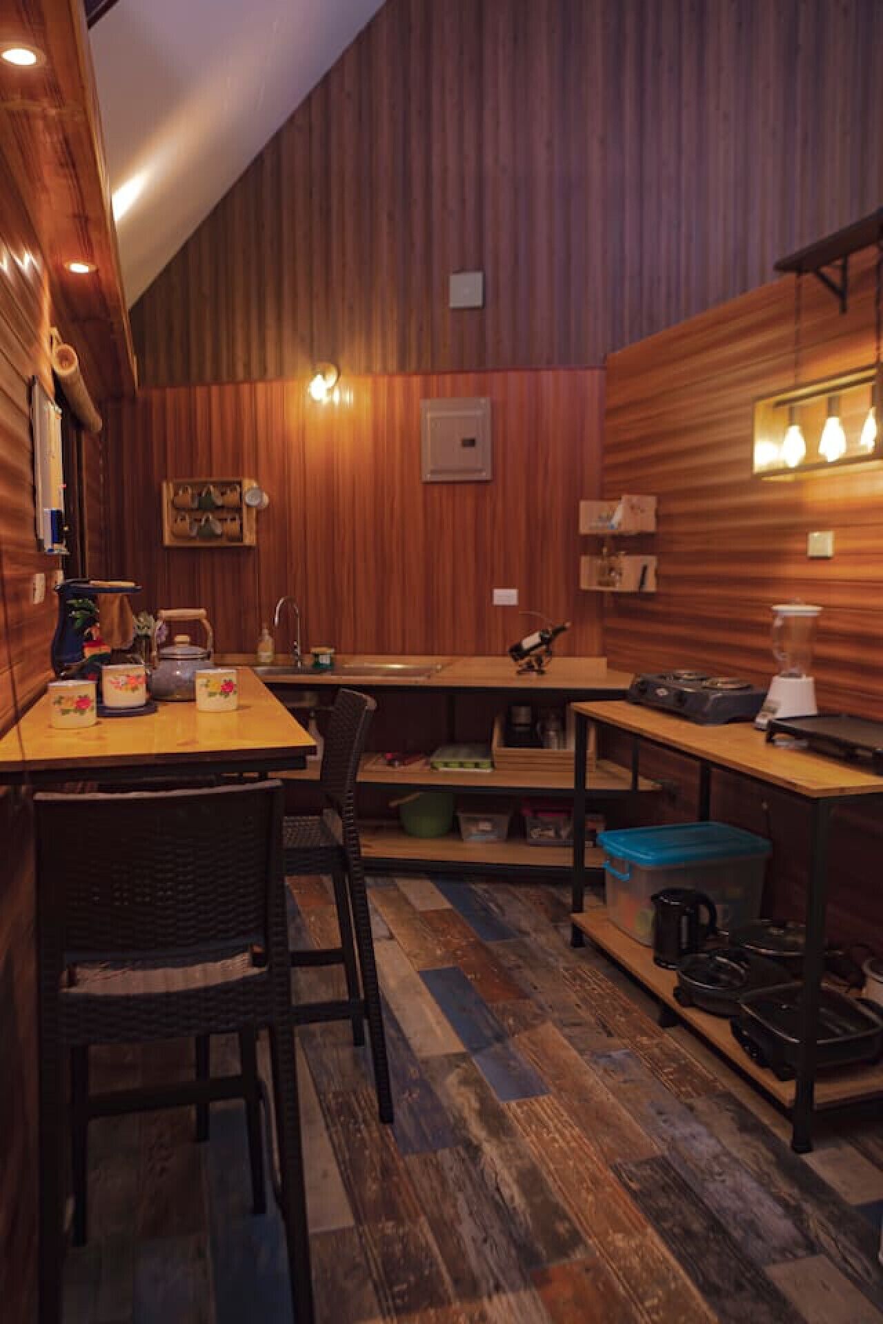 Een gezellige kamer met houten lambrisering, een eettafel, stoelen en een keuken met inbouwapparatuur.