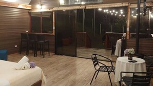 Een ruime kamer met een groot bed, een eettafel met stoelen en een hoog plafond met houten balken.