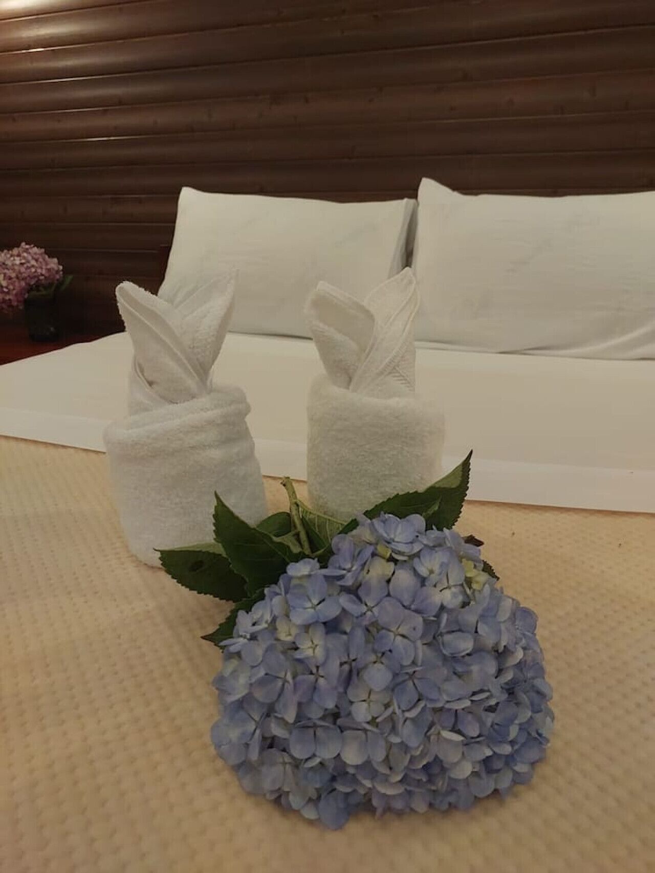 A neatly arranged bed with white linens and two white towels placed on the side.