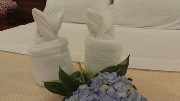 A neatly arranged bed with white linens and two white towels placed on the side.
