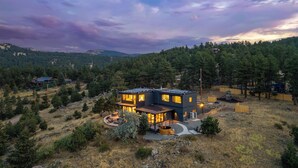 A modern house with a patio area, surrounded by a forested landscape. - Boulder Luxury: Panoramic Mountain Views, Cedar Hot Tub, Wellness and Romance! (Boulder)