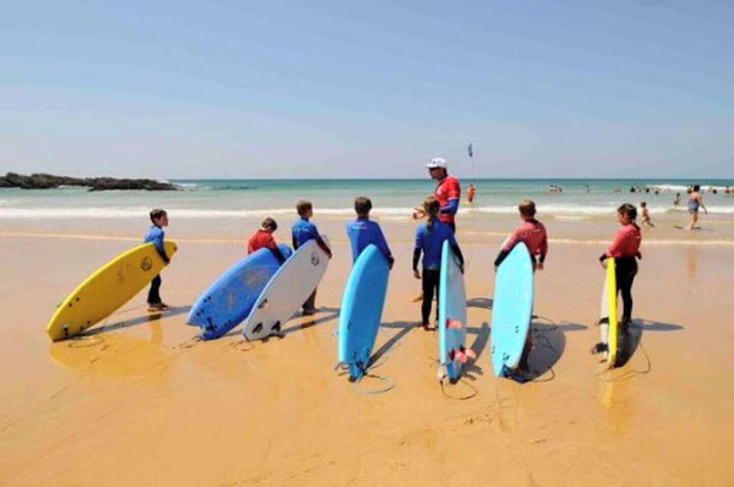 A beach with people holding surfboards.