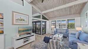 A spacious living room with a large TV, comfortable seating, and a view of the outdoors.