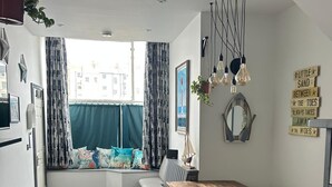Una habitación acogedora con un ventanal grande, una mesa de madera, bancos y vistas a edificios.