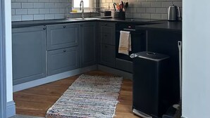 Una cocina moderna con gabinetes grises, encimera negra y extractor de acero inoxidable.