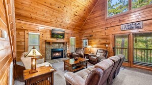 A cabin interior with a stone fireplace, leather seating, and a sign indicating cabin time.