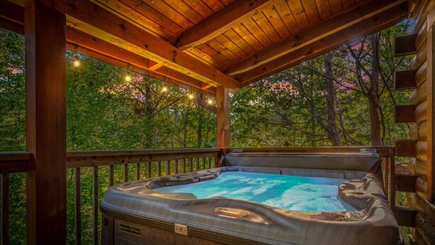A hot tub in a wooden deck area with a view of trees.