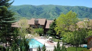 A two-story building with a swimming pool and a mountain backdrop. - Cozy Mountain Retreat WL802| Community Hot Tub (Eden)