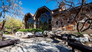 A building with a stone facade and wooden accents, surrounded by a landscaped area with benches and rocks. - Cozy Mountain Retreat WL802| Community Hot Tub (Eden)