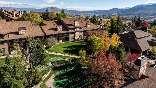 A residential area with multiple houses, a well-maintained lawn, and a view of distant mountains. - Cozy Mountain Retreat WL802| Community Hot Tub (Eden)
