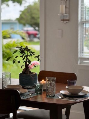 A dining table set with a potted plant, two glasses, a candle, and a bowl.