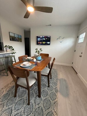 A dining area with a wooden table, chairs, and a ceiling fan.