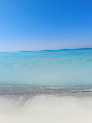 A beach with clear turquoise water and a sandy shore.