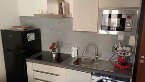 Eine kleine Küche mit Kühlschrank, Mikrowelle, Spüle und Waschmaschine.