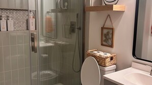 Une salle de bain moderne avec une douche à parois de verre, des toilettes et un meuble-lavabo avec un miroir.