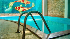 Ein Schwimmbecken mit einem Wandgemälde von Koi-Karpfen und einer Metallleiter.