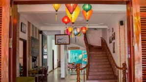 Eine Hotellobby mit Treppe, Empfangstresen und bunten Hängeleuchten.