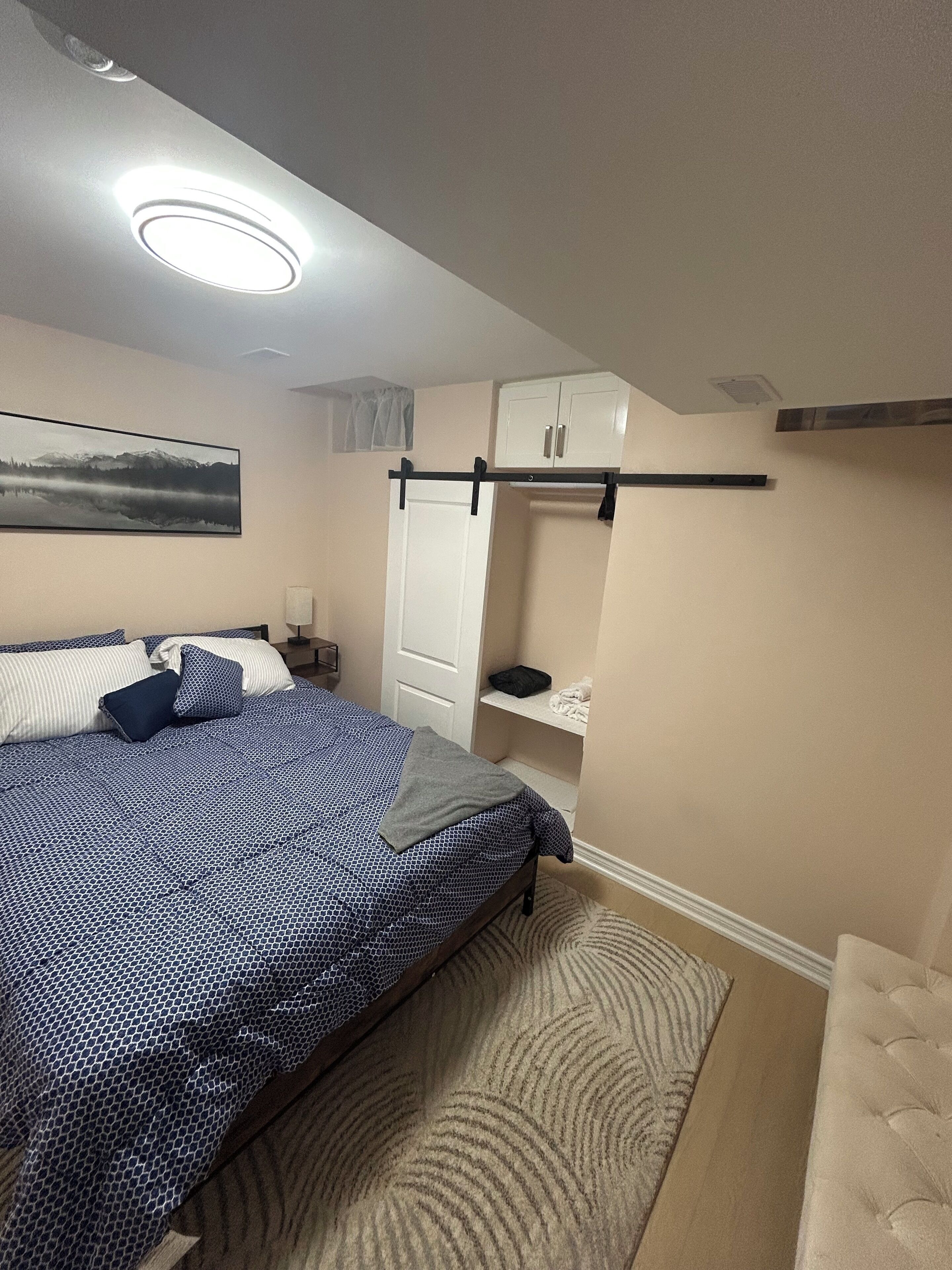 A bedroom with a bed, a nightstand, a wardrobe, and a painting on the wall.