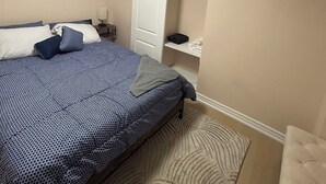 Een slaapkamer met een bed, nachtkastje, kledingkast en een schilderij aan de muur.