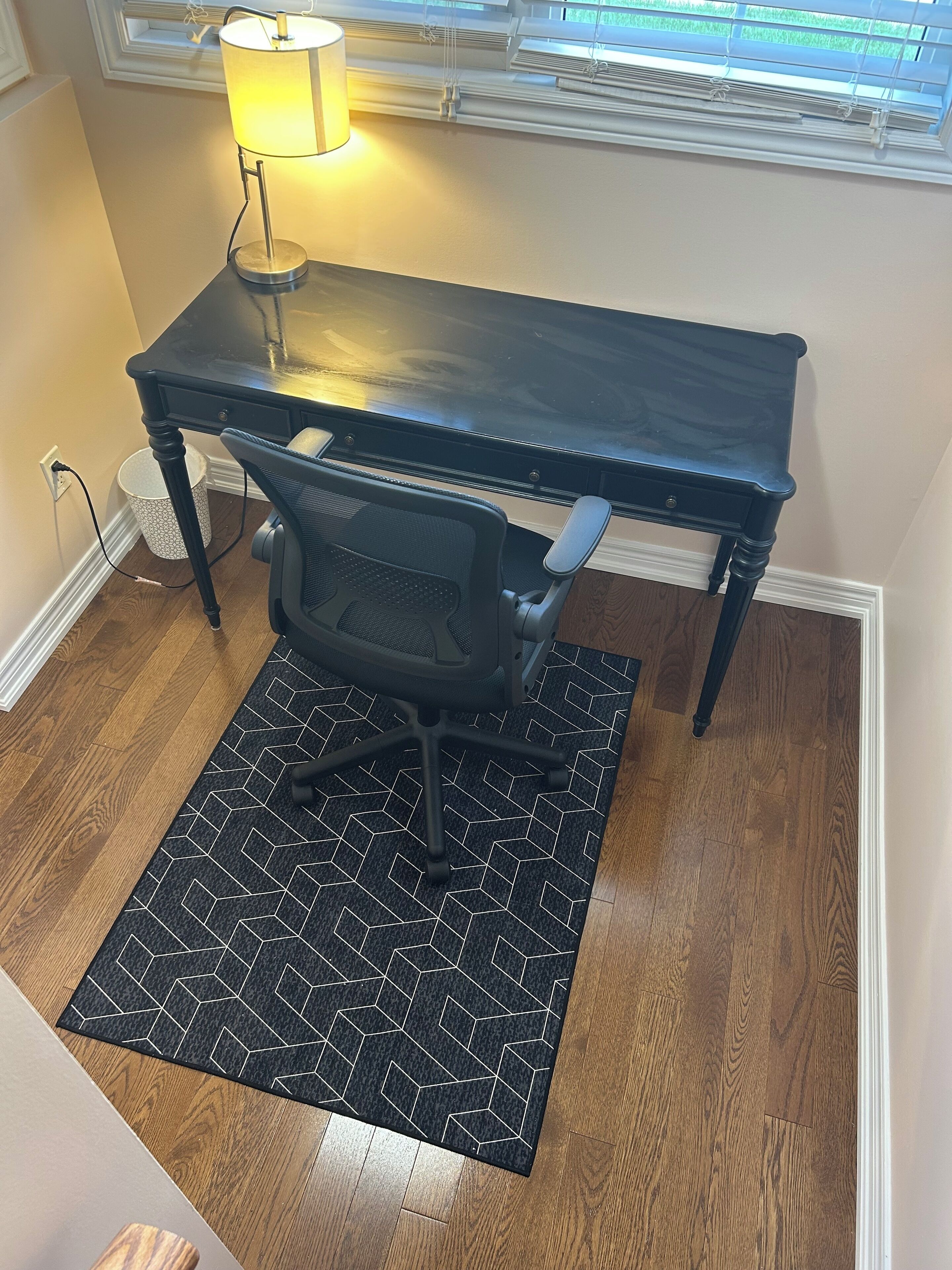 Un petit bureau comprenant un bureau, une chaise et une lampe.