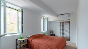 A bedroom with a bed, a small table, a chair, a wardrobe, and a window.