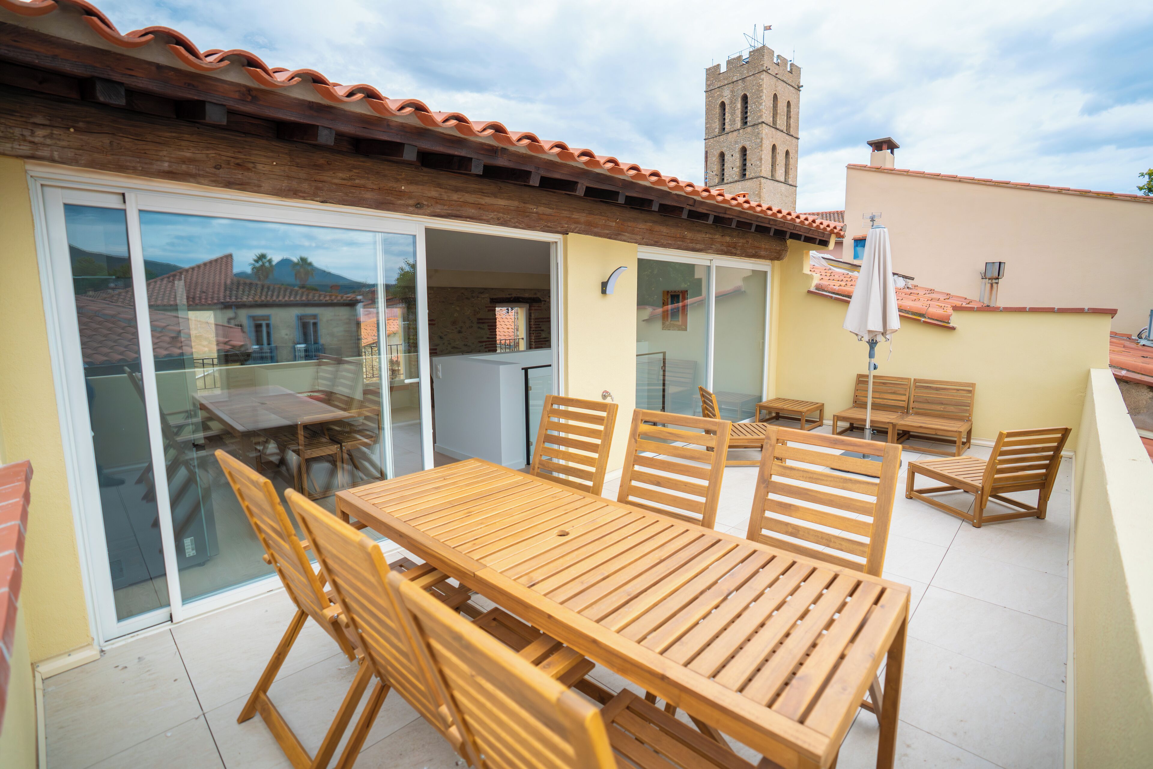 A wooden table and chairs on a patio with a view of a tower.
