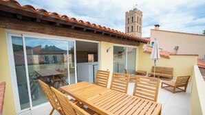 A wooden table and chairs on a patio with a view of a tower.