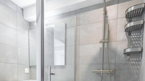 A modern bathroom with a glass-enclosed shower, a wooden vanity, and a large mirror.