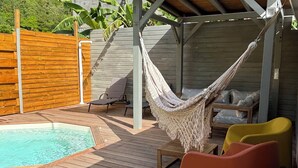 Une terrasse en bois avec une piscine, un hamac et deux chaises.