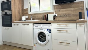 Une cuisine moderne équipée d’appareils électroménagers Bosch, d’un lave-linge et d’un téléviseur à écran plat.